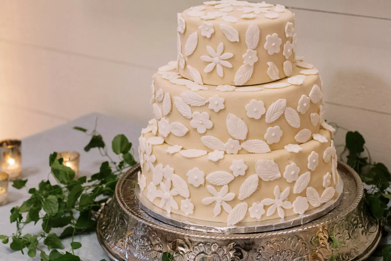 A tiered wedding cake on a table with greenery