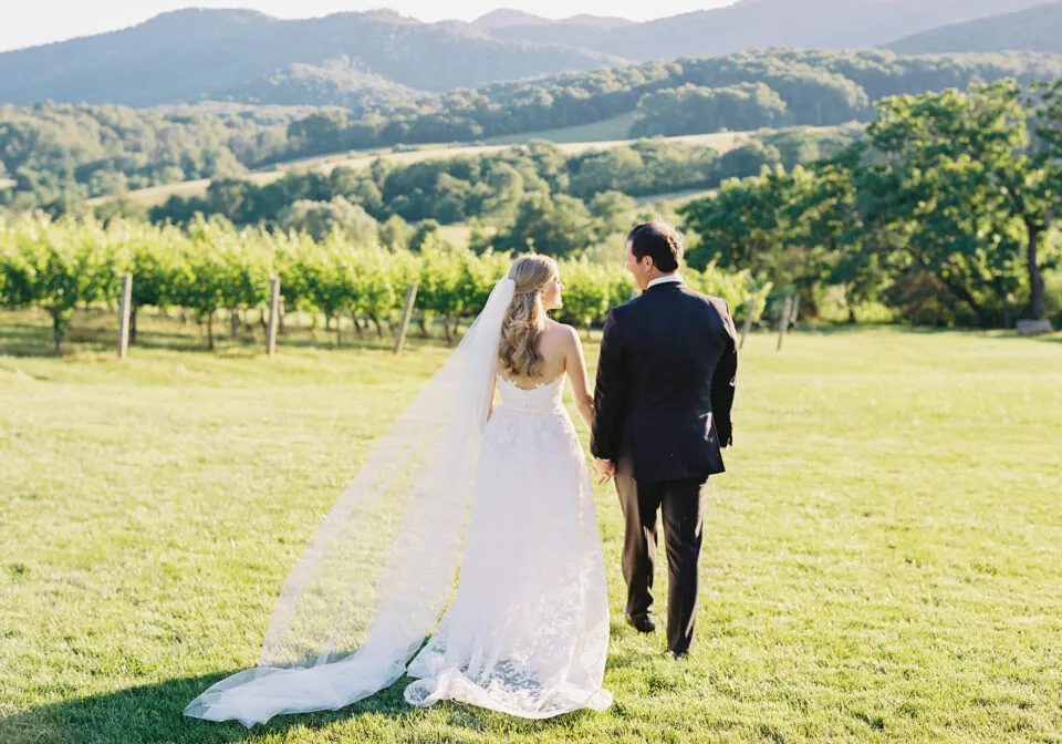 A bride and groom walking in a green hilly landscape